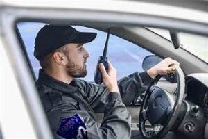 A security guard in a car while talking on his radio.