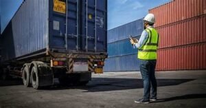 An industrial security guard guiding a truck in front of him.