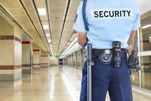 A security guard looking at an emply mall with his back towards the camera.