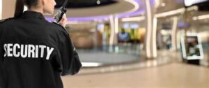 A female security guard showing her back towards the camera and answering her radio inside a mall.
