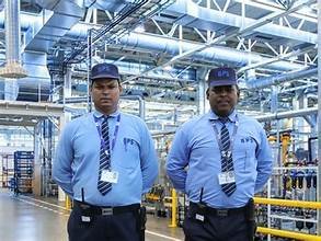 Two Industrial security guards in stance in front of machinery.