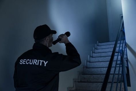 A man holding a flashlight upwards to a flight of stairs in front of him.