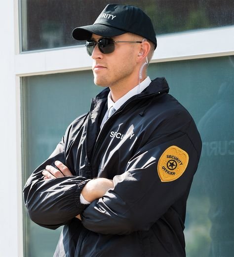 A man in a security jacket crossing his arms and looking in front of him.